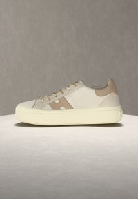 Baskets beige et blanc cassé avec logo "H" marron clair sur le côté, semelle épaisse couleur crème et languette de talon assortie en marron clair, vues de profil.