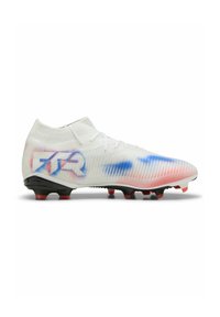Botín de fútbol blanco con parte superior de punto ajustada, que presenta acentos en azul y rojo, textura estriada y suela negra con tacos rojos.