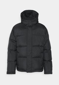 Veste matelassée noire avec un col montant et une capuche. Comprend des sections matelassées, des poches avant et une fermeture éclair pour l'isolation.