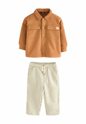 Brun skjortejakke med to forlommer kombineret med cremefarvede elastik-bukser med tynde lodrette brune striber.