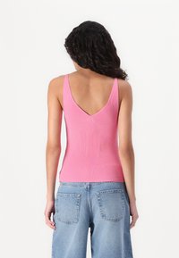 Ribbet lyserød tanktop med V-rygdesign, kombinert med lyseblå vidbukser i denim. Myk stofftekstur og tettsittende silhuett.