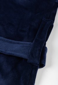 Laivastonsininen puuvillafroteekangas pystysuuntaisilla urituksilla; sisältää taitetun hihansuun yksityiskohdan. Tekstuuri on pehmeä ja pörröinen, tarjoten tukevan tuntuman.