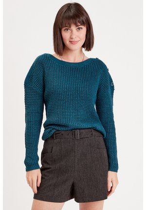 Suéter de punto en color azul verdoso con mangas largas, textura acanalada, escote amplio y detalle de botones en el hombro, combinado con pantalones cortos grises.