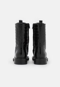 Botines de charol negro con textura de cocodrilo, cierre de cremallera en la parte trasera y suela negra resistente, con un tacón corto.