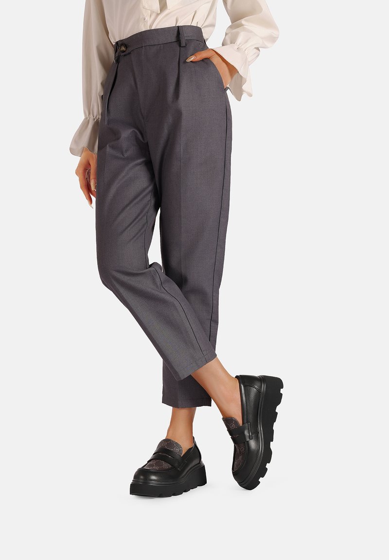 Pantaloni grigi a sigaretta con vita alta e tasche laterali; abbinati a mocassini neri con zeppa e un accento a motivo.