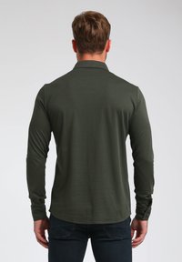Langärmliges Poloshirt aus dunkelgrünem Stoff, mit Kragen und Knopfverschluss, glatter Textur und taillierter Silhouette.