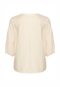Blouse crème avec manches trois-quarts bouffantes et poignets élastiques, vue de dos sur fond blanc.