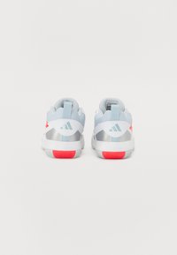 Chaussures de sport blanches et bleu clair avec des accents argentés et des semelles roses. Tige en tissu texturé, col rembourré, et logo Adidas sur les talons.