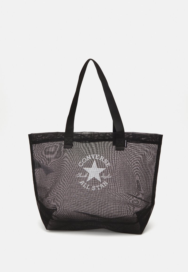 Sac fourre-tout en maille noire avec deux poignées robustes, arborant un logo Converse blanc au centre et une forme rectangulaire. Matériau texturé.