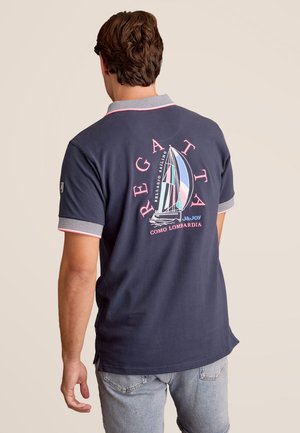 Marine polo met een gestreepte kraag en roze accenten, met een zeilgrafiek op de achterkant. Korte mouwen, casual pasvorm.