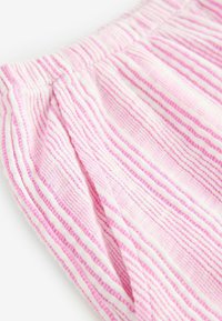 Tissu à rayures roses et blanches avec un motif texturé, présentant une taille froncée et un matériau doux et léger.