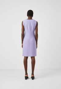 Liliowa sukienka bez rękawów o dopasowanym kroju, sięgająca powyżej kolan, z zamkiem błyskawicznym z tyłu i gładkim, teksturowanym materiałem.