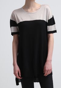 Haut noir et argent métallique à manches courtes, avec un col rond, des rayures horizontales et une longueur de dos plus longue. Texture douce.