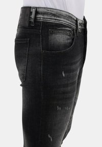 Zwarte denim jeans met een slim fit, met een vervaagde textuur, versleten accenten en een label met een schedelontwerp op de tailleband.