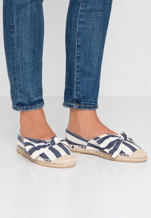 Raidalliset espadrillesit, joissa on sinivalkoinen kuvio, kangasosa, rusettiyksityiskohta ja kudottu juuttipohja. Yhdistetty sinisiin farkkuihin.