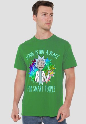 Man wearing green T-shirt with animated character and text "School is not a place for smart people" on a plain background.
