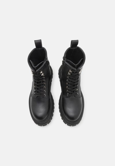 Črne usnjene gležnjarje z vezalkami spredaj, srebrnimi očesci, stranskim zadrgo in gumijastim podplatom. Gladka tekstura z zanko na zadnji strani.