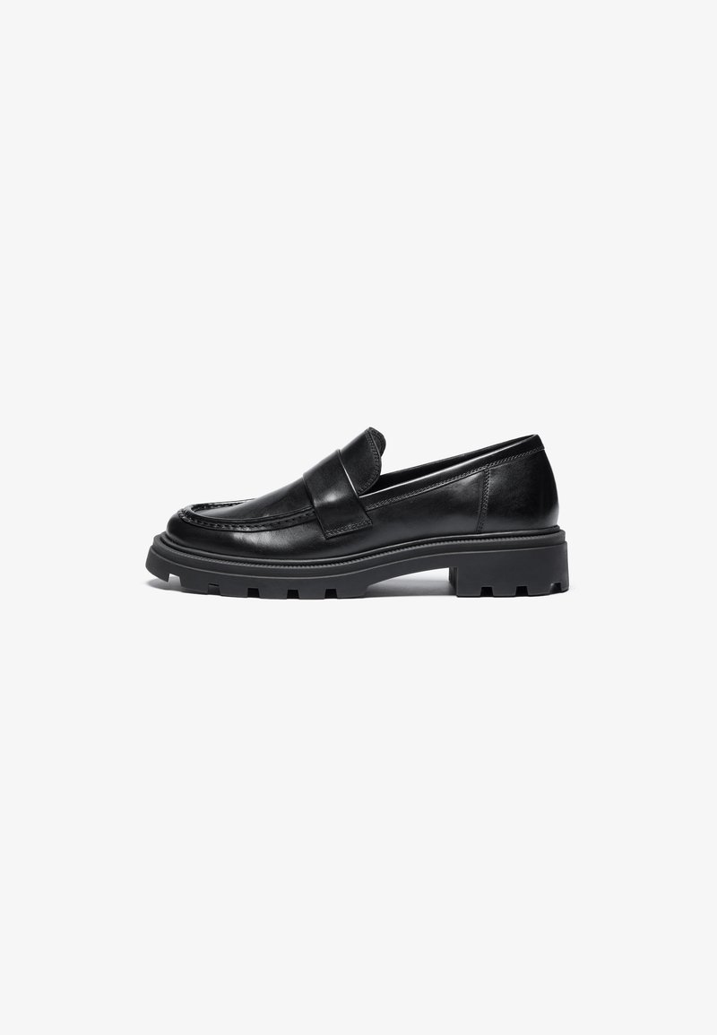 Mocassins de couro preto com ponta arredondada, detalhes costurados e uma sola de borracha grossa com um padrão de tração texturizado.