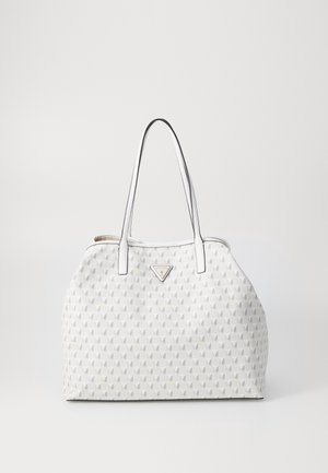 Biała torebka z geometrycznym wzorem, podwójnymi uchwytami i trójkątnym logo Guess z przodu, na jednolitym białym tle.