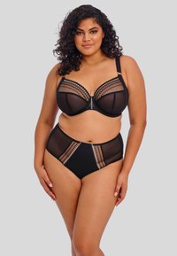 Ensemble de lingerie noir comprenant un soutien-gorge transparent avec des accents à pois et une culotte haute assortie avec des embellissements et des panneaux en maille.