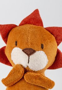 Stuffed lion toy with a soft, orange body, red fabric mane, and a white snout. Features embroidered eyes and a rounded shape.