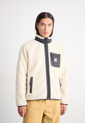 Chaqueta de forro polar crema con detalles en negro, cuello alto, cremallera frontal y un bolsillo en el pecho. Presenta una textura de tela y un dobladillo ajustable.