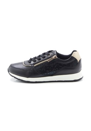 Baskets noires avec semelle blanche, patch beige au talon, fermeture éclair latérale, lacets et motif texturé subtil sur la partie latérale.