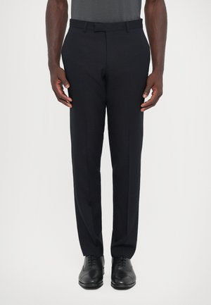 Pantaloni in tessuto blu scuro con vestibilità su misura, frontale piatto e due tasche laterali, abbinati a scarpe eleganti nere.