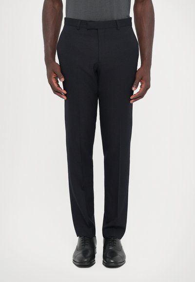 Pantaloni in tessuto blu scuro con vestibilità su misura, frontale piatto e due tasche laterali, abbinati a scarpe eleganti nere.