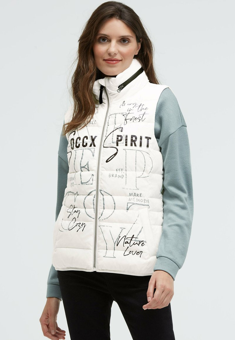 Weiße, gepolsterte Weste mit gesteppten Details, schwarzen Textdrucken und Stehkragen. Die Seiten zeigen ein graues Langarmgarment.