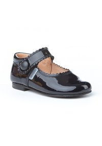 Zapato Mary Jane de charol negro con borde en forma de onda, correa simple con cierre de botón, punta redondeada y tacón bajo.