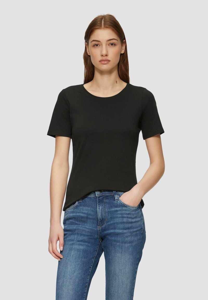 T-shirt nera a maniche corte realizzata in tessuto morbido e liscio. Collo rotondo e vestibilità rilassata, abbinata a jeans blu. Design minimalista, senza motivi.