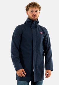 Abrigo azul marino resistente al agua con capucha, cierre frontal de cremallera, bolsillos laterales y un detalle de logo circular en el pecho.