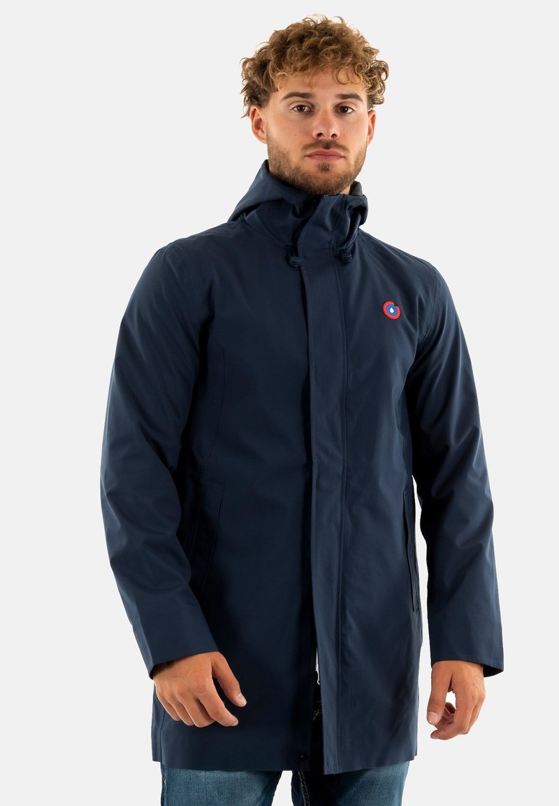 Abrigo azul marino resistente al agua con capucha, cierre frontal de cremallera, bolsillos laterales y un detalle de logo circular en el pecho.