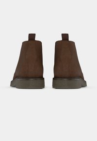 Rudi zomšos aulinukai su tekstūruota gumine padų dalimi ir kilpomis. Šonuose matomos siūtos detalės. Lygiapadžiai.