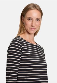 Czarny i beżowy pasiaste długorękawowy top z okrągłym dekoltem. Miękka tkanina, luźny krój, z delikatnym detalem guzikowym na ramieniu.