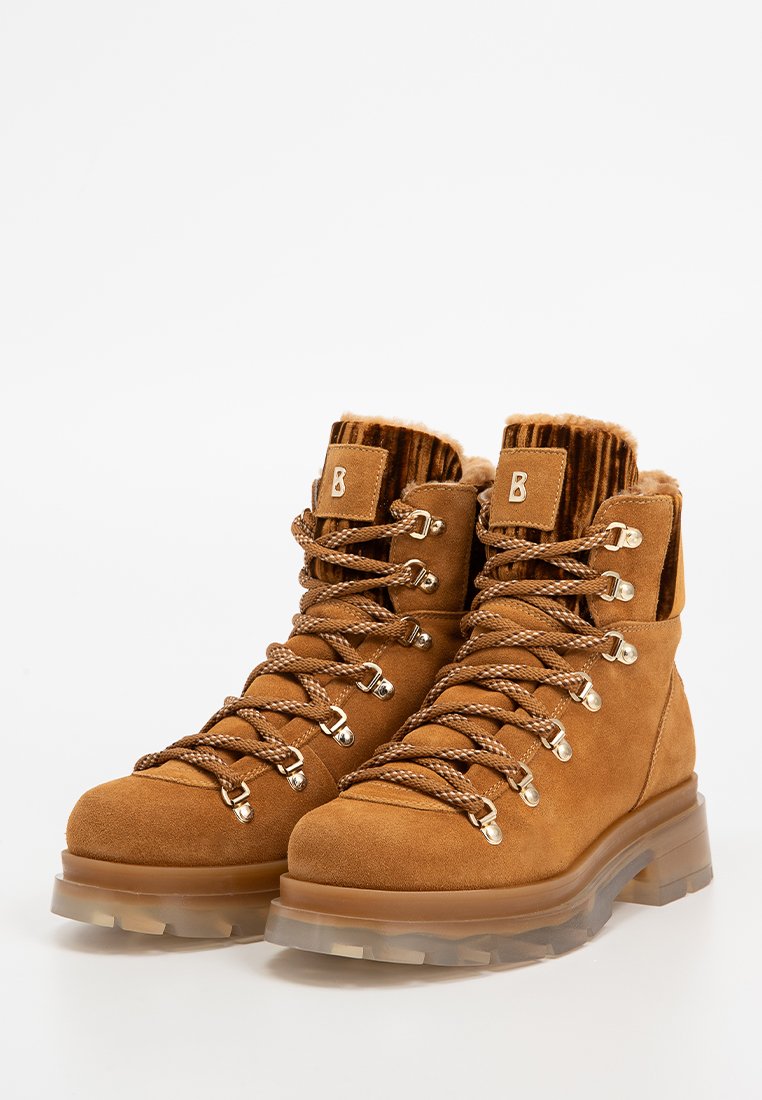 Braune Wildleder-Wanderschuhe mit einem gerippten oberen Schaft, metallischen Ösen und einer klaren Gummisohle. Verfügt über dicke braune Schnürsenkel und ein geprägtes Logodetail.