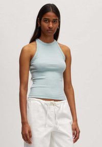Lichtblauw geribbeld tanktop met een hoge halslijn en mouwloos ontwerp, gecombineerd met witte broek met trekkoord. Glad van structuur, aansluitende stijl.