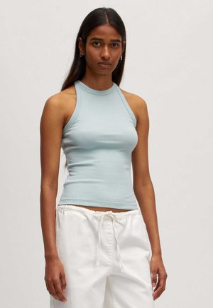 Himmelblaues gestreiftes Tanktop mit hohem Ausschnitt und ärmellosem Design, kombiniert mit weißen Jogginghosen mit Kordelzug. Glatte Textur, figurbetonter Stil.