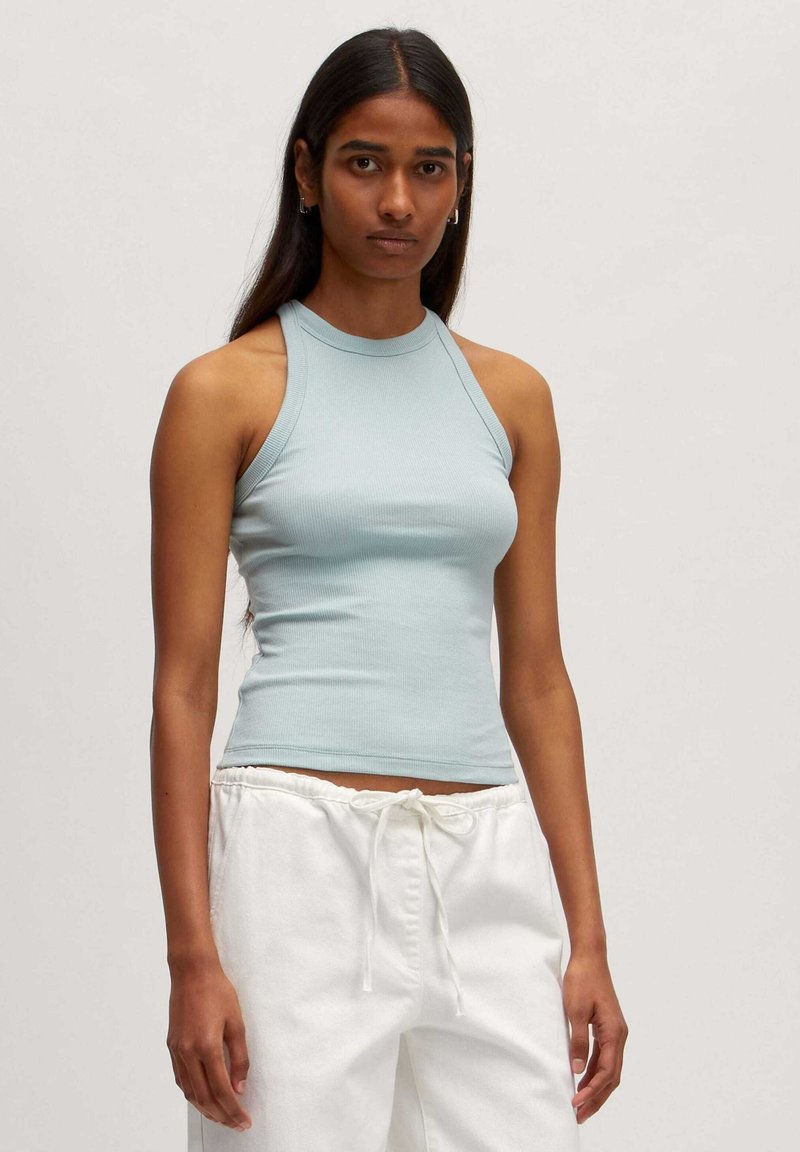 Lichtblauw geribbeld tanktop met een hoge halslijn en mouwloos ontwerp, gecombineerd met witte broek met trekkoord. Glad van structuur, aansluitende stijl.