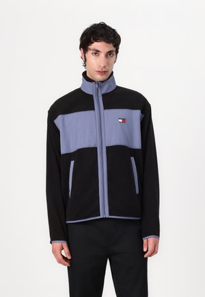 Fleece jacket in black and light blue, featuring a high neck, front zipper, side pockets, and a small logo on the chest.