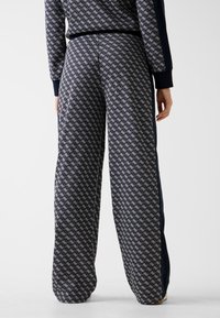 Marineblauwe sweatpants met een geometrisch patroon, voorzien van een elastische tailleband en contrasterende zijpanelen voor extra detail.