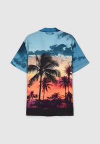 Camicetta a maniche corte con un vivace design di tramonto tropicale, con palme in silhouette che sfumano blu, arancione e rosa.