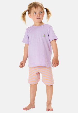 Young child with blonde hair in pigtails wearing a light purple t-shirt with a small green apple and orange and purple striped shorts, barefoot.