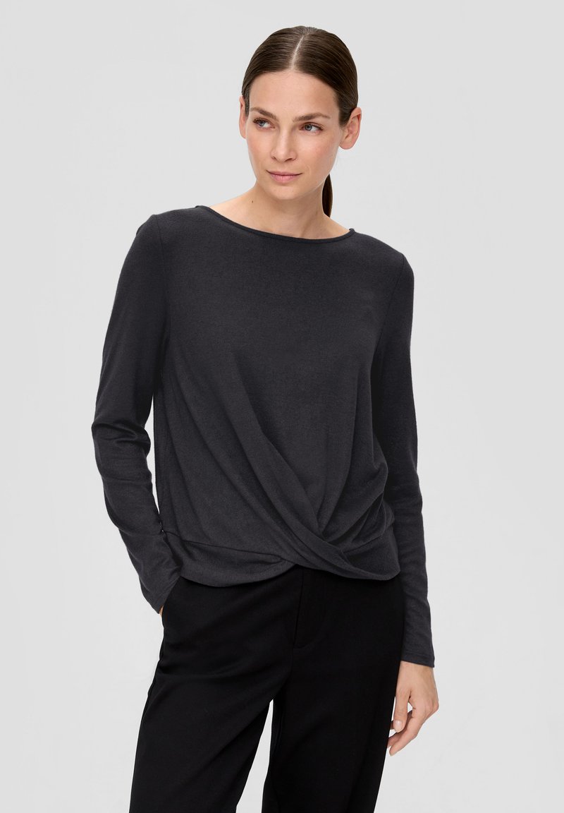 Langärmliges, dunkelgraues Oberteil mit rundem Ausschnitt, verdrehtem Vorderdesign und weicher Textur. Kombiniert mit schwarzen Hosen.