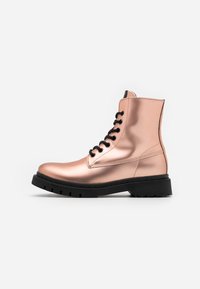 Metalliska roséguldiga combat boots med svarta snören, en platt sula och midikotslängd, med en slät textur och robust design.