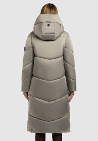 Langer, hellgrauer Daunenmantel mit hoher, gepolsterter Kapuze, Chevron-Steppmuster und seitlichen Reißverschlüssen. Verfügt über schwarze Knopfakzente.