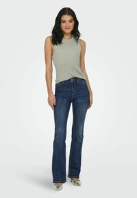 Lichtgroene geribbelde tanktop gecombineerd met donkerblauwe flared jeans. De tanktop heeft een ronde hals en de jeans beschikken over een klassiek vijf-pocket ontwerp.