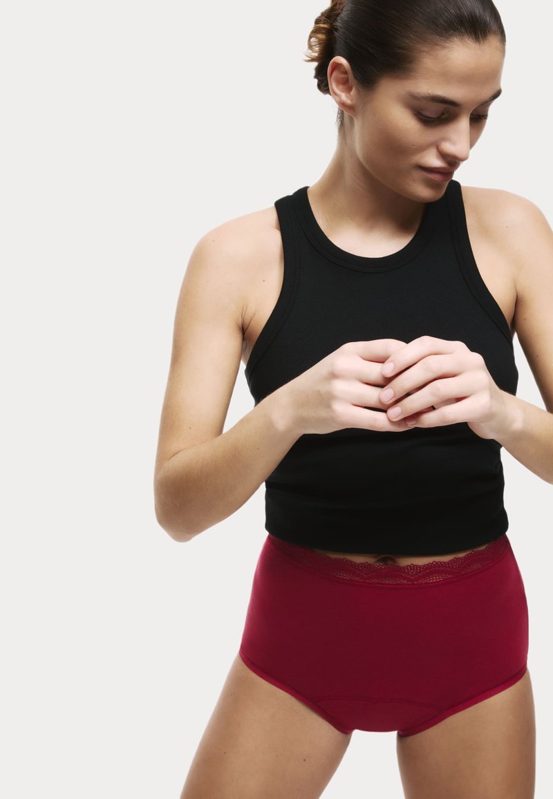 Débardeur noir à côtes associé à une culotte bordeaux taille haute avec une bordure en dentelle à la taille. Texture lisse, design simple.