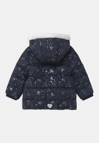 Veste matelassée bleu marine avec une capuche doublée en faux-fur. Présente des motifs métalliques en étoiles et en cœurs, un design matelassé et des poignets élastiques.